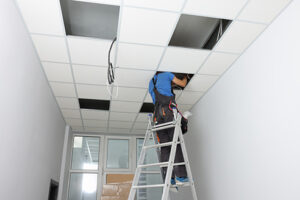Installing ceiling lighting. Electrician working on step ladder