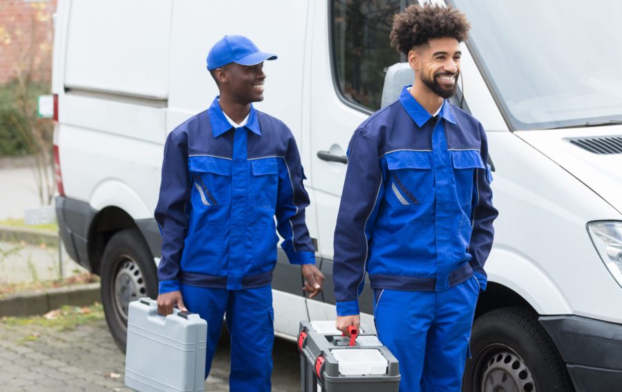 Portrait Of Two Smiling Manual Workers With Their Tool Boxes Standing Near The White Van